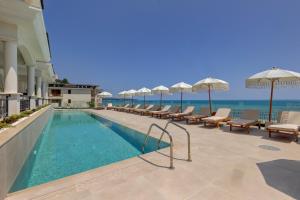 ein Swimmingpool mit Liegen und Sonnenschirmen und das Meer in der Unterkunft La Boheme - Adults Only in Obsor
