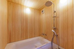 伊势市Nipponia Hotel 伊勢河崎 商人町的一间带浴缸和淋浴的浴室,拥有木墙