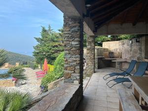 an outdoor patio with chairs and a stone wall at Vacances de rêve vue mer et montagne in Brando