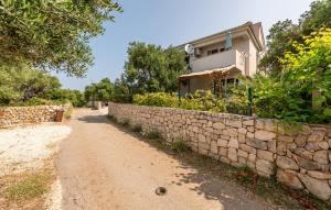 a house with a stone wall next to a dirt road at 2 Bedroom Nice Apartment In Jakisnica in Jakišnica