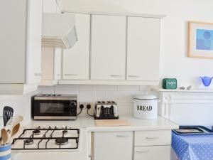 eine weiße Küche mit einem Herd und einer Mikrowelle in der Unterkunft St Mary's House in Penzance