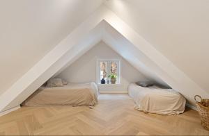two beds in a attic room with white walls and wooden floors at Idylliske Nordbyen - Brygga i Tønsberg in Tønsberg