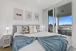 a bedroom with a large bed and a balcony at Palm & Sea Trinity Beach in Trinity Beach