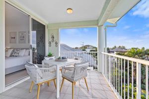 a patio with a table and chairs on a balcony at Palm & Sea Trinity Beach in Trinity Beach