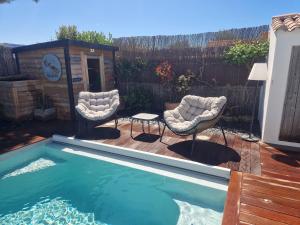 a backyard with a swimming pool and two chairs and a table at Villa la Ferlandiere in Sainte-Marie-de-Ré +6 photos