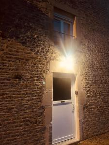 Una ventana con un televisor en el costado de un edificio de ladrillo. en La Chance Spa cottage 6 personnes, en Orges
