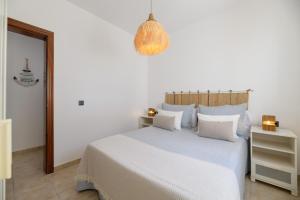 a white bedroom with a bed and a chandelier at Mariate II Descanso y vistas al Mar in Punta de Mujeres