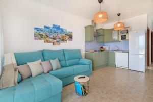 a living room with a blue couch and a kitchen at Mariate II Descanso y vistas al Mar in Punta de Mujeres +11 photos