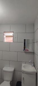 a white bathroom with a toilet and a window at Cantinho Do Sossego in Nova Iguaçu
