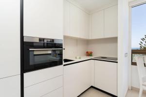 a kitchen with white cabinets and black appliances at Ocean View Playa del Aguila in Playa del Aguila +21 photos