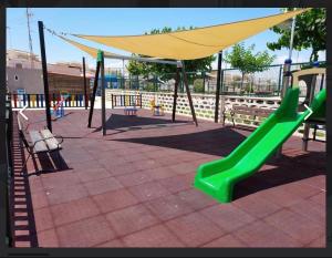 a playground with a green slide and a yellow canopy at Villa Banfield in Gran Alacant