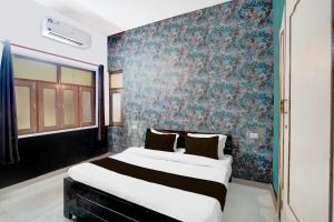 a bedroom with a large bed with a blue wall at Super Hotel O The Comfort in Kānpur