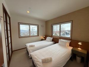 a hotel room with two beds and two windows at Yutaka 2 in Kutchan
