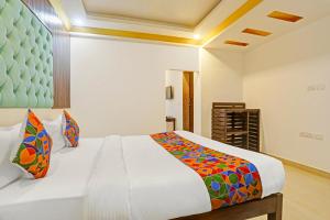 a bedroom with a large white bed with colorful pillows at FabHotel 22 Squares Living Spaces - Nr Calangute Beach in Calangute