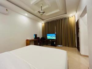 a bedroom with a white bed and a television at Lavilla Lake Resort And Restaurant in Kollam