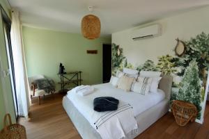 a bedroom with a white bed with a black bag on it at Les Suites in Camiers +51 photos