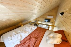 a bed in a small room with a wooden ceiling at Le Filet Tendu in Marmoutier