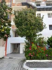 a tree in front of a building with flowers at Grediv Apartment Orikum in Orikum