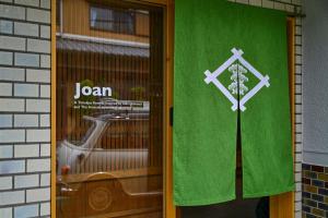eine grüne Tür mit einem Schild darauf in der Unterkunft 宿Joan in Sakurai