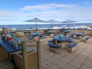 a group of tables and umbrellas on the beach at Wombats Burrow 20 Duck pool Hedlywood in Bridgerule