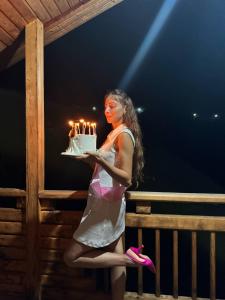 a woman is holding a birthday cake with lit candles at LIVANi in Batumi