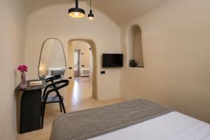 een slaapkamer met een bed en een tafel met een spiegel bij Calissa Suites by Ananda in Pirgos