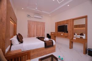 a bedroom with a bed and a mirror and a television at Hotel Sahaya Arasi in Kovakulam
