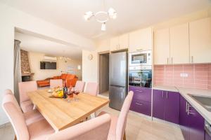 a kitchen and dining room with a wooden table and purple cabinets at Villa Roz by Villa Plus in Plateies