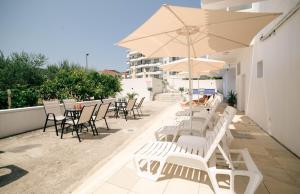 a patio with chairs and tables and an umbrella at Villa Champion in Ulcinj