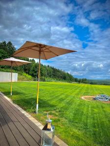a wooden deck with an umbrella and a field at Business Apartment inkl Frühstück in Seiwerath