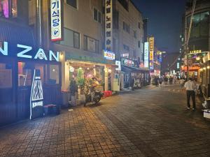 eine Stadtstraße bei Nacht mit Menschen und Schildern in der Unterkunft Soul of Seoul - Cozy 3 room stay, 3min from SNU Station in Seoul