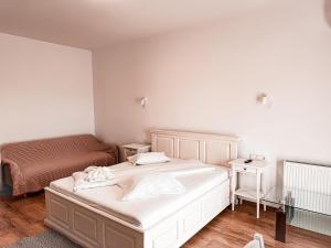 a bedroom with a white bed and a couch at EMSI Apartment in Sebeş