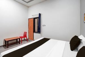 a bedroom with a bed and a red chair and a table at Hotel O Vikas INN 2 in Bāra Banki