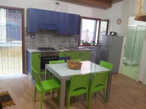カステッランマーレ・デル・ゴルフォにあるLa perla sul golfoのキッチン(緑のキャビネット、テーブル、緑の椅子付)