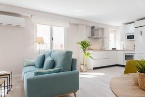 a living room with a blue couch and a kitchen at Apartamento Catedral in Almería