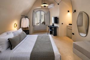 een slaapkamer met een groot wit bed en een spiegel bij Calissa Suites by Ananda in Pirgos +34 foto's
