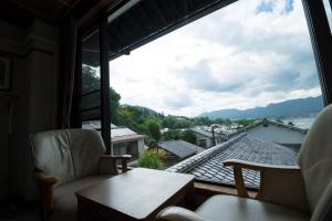 a room with a large window with a table and chairs at Miyajima Guest House Mikuniya in Miyajima +86 photos