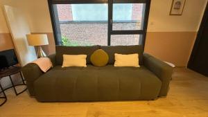 a green couch in a living room with a window at Quiet and central, 6p fully equipped in Arras