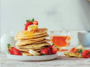 a stack of pancakes with strawberries on a plate at Segara Seaside Resort in Nusa Lembongan