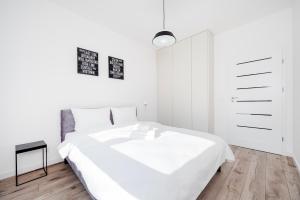 a white bedroom with a bed and a dresser at Widzewska Superior Apartment by BookingHost in Łódź