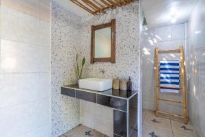 ein Badezimmer mit einem Waschbecken und einem Spiegel an der Wand in der Unterkunft Villa Kupu-Kupu, private pool & lush garden in Gili Air
