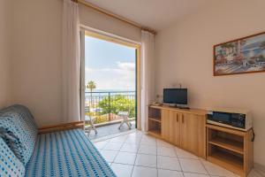 a bedroom with a bed and a television and a balcony at San Matteo Apartments in Loano