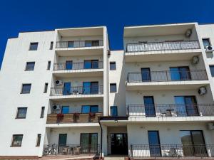 a white apartment building with balconies and a blue sky at EMSI Apartment in Sebeş