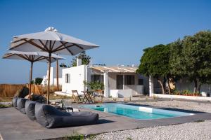 a swimming pool with an umbrella and lounge chairs and a swimming poolvisor at Freya Villa in Skiros