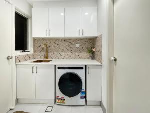 a kitchen with a washing machine in a white kitchen at MetaWise Cozy Family Room in Shared Home Free Parking in Castle Hill +8 photos