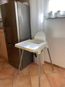 a white stool in a kitchen next to a refrigerator at Ferienwohnung im Sand in Herbolzheim
