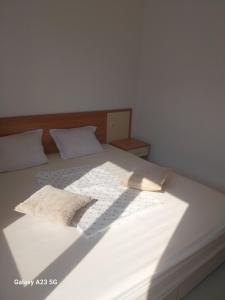 ein großes weißes Bett mit zwei Kissen darauf in der Unterkunft Апартамент Бяла in Byala + 7 Fotos
