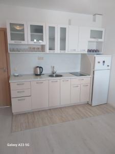 eine weiße Küche mit Spüle und Kühlschrank in der Unterkunft Апартамент Бяла in Byala