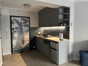 a kitchen with a painting of a sailboat on the wall at La Marina in Władysławowo
