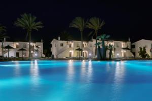a large swimming pool at night with white houses at AluaSun Mediterráneo in S'Algar